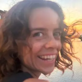 Ellen laughing by the water at sunset